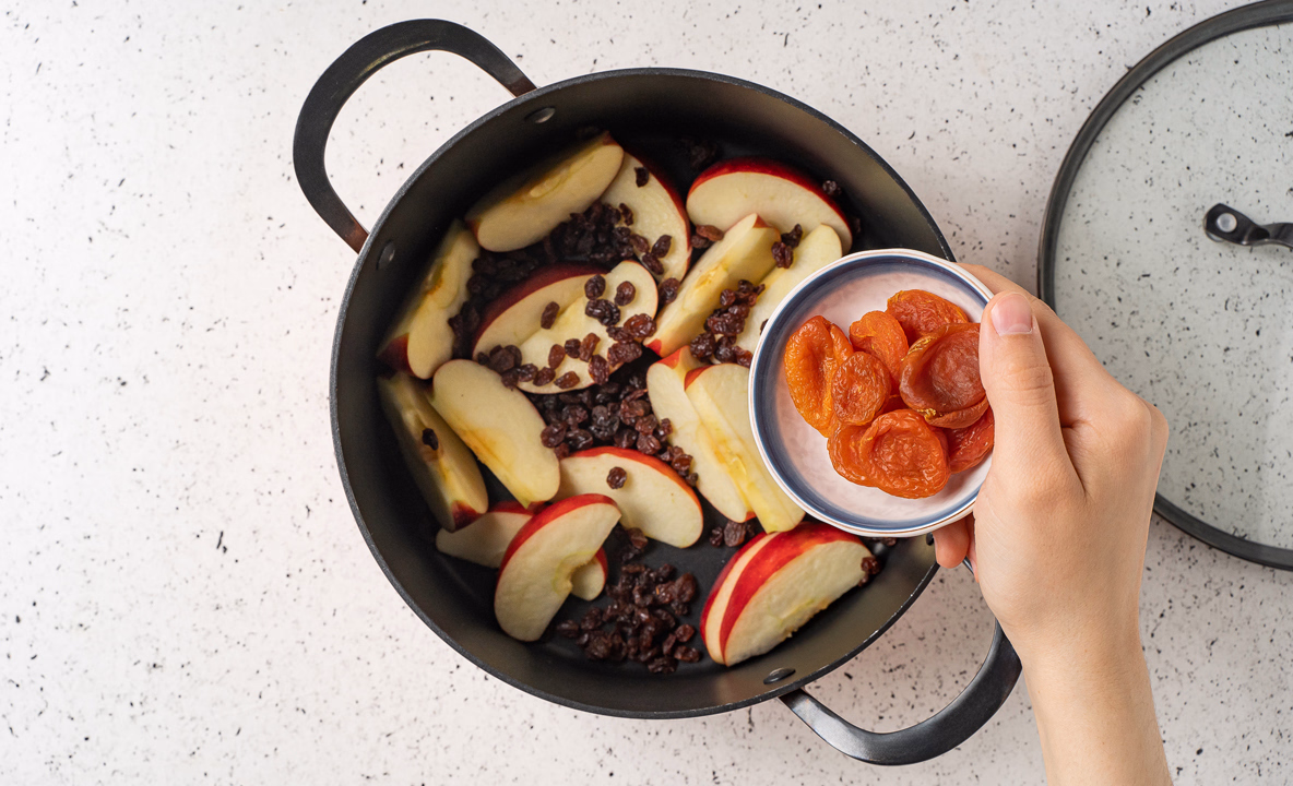 На фото кастрюля с яблоками, изюмом и курагой