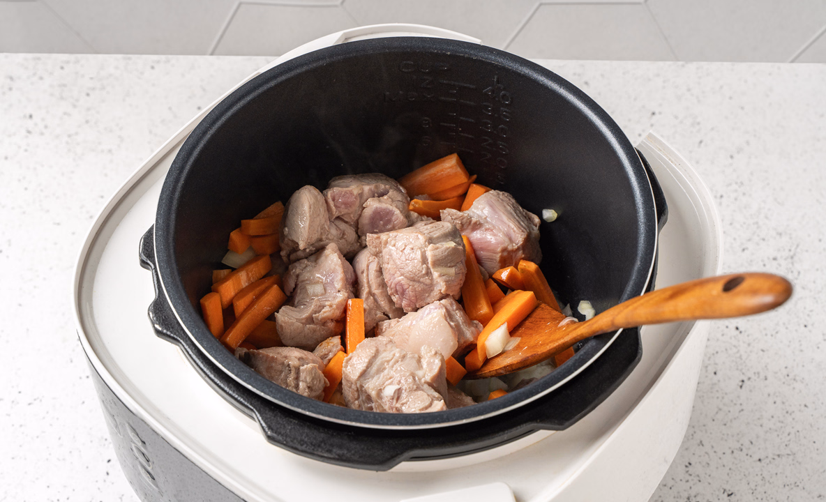 Лук и морковь перемешали с мясом в чаше мультиварки.