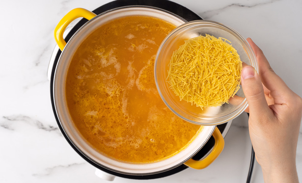 Лапша из тврелочки пересыпается в кастрюлю с бульоном, курицей и овощами